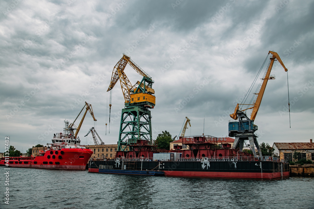 Cargo cranes and barges at the sea port