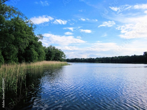Picturesque lake at Poland, Masuria - region in northern Poland famous for its lakes. Blue lake water and blue sky with clouds