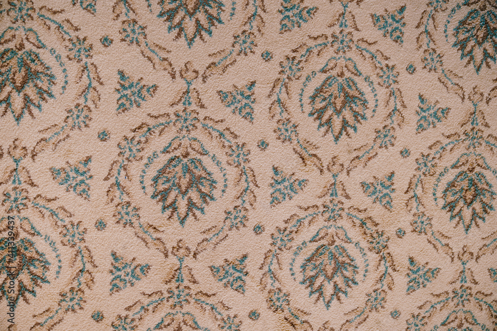 Close-up of a carpet texture with patterns in the form of a floral ornament.