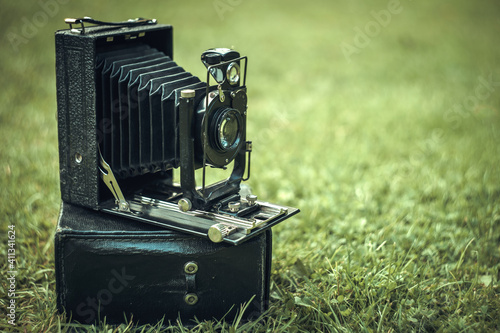 Black retro camera accordion on green grass photo