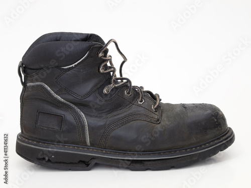 An old, worn, black leather work boot with a cracked rubber sole is shown isolated against white from a side view.