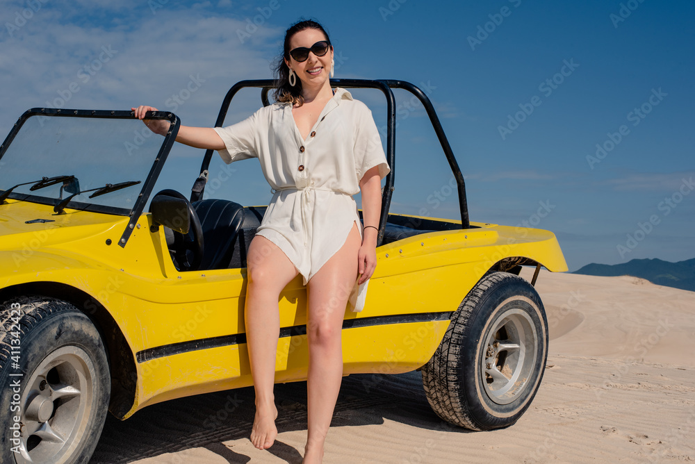 Woman leaning on the car on sand dunes