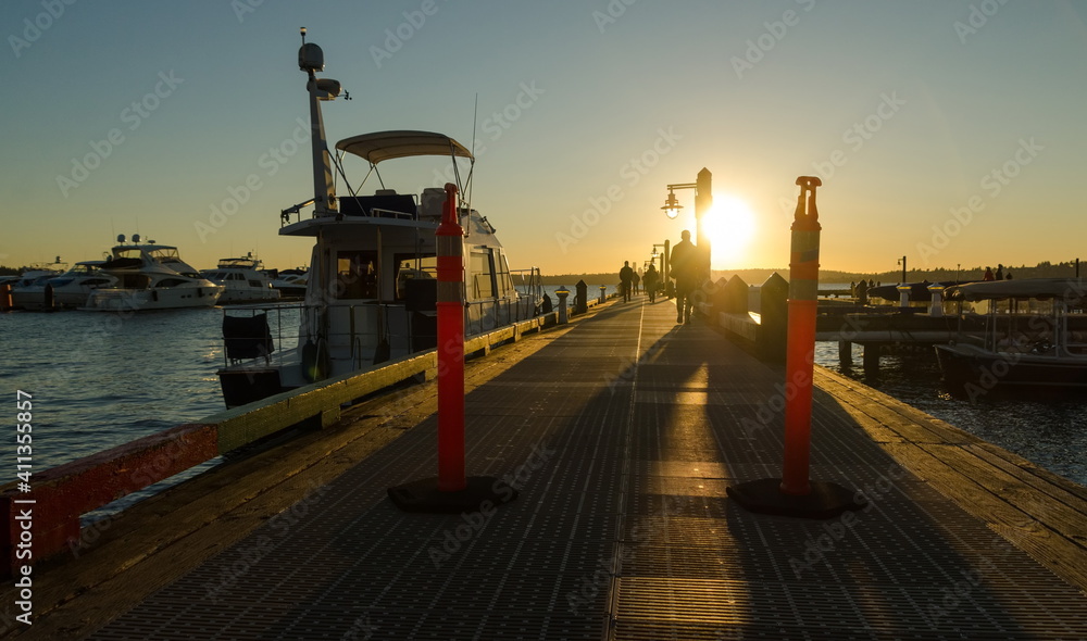 Sunset watchers walking to  sun on a wooden pier