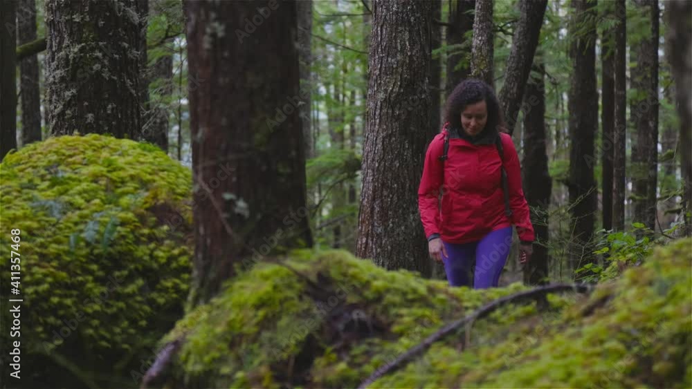 Girl Hiking on a Path in the Rain Forest during a rainy Winter Season. Squamish, North of Vancouver, British Columbia, Canada. Slow motion Girl Hiking on a Path in the Rain Forest during a rainy Winter Season. Squamish, North of Vancouver, British Columbia, Canada. Slow motion