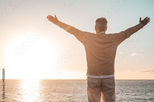old man looking to the sunset and the sea with opened arms feeling free and happy - freedom and happiness feel lifestyle and concept photo