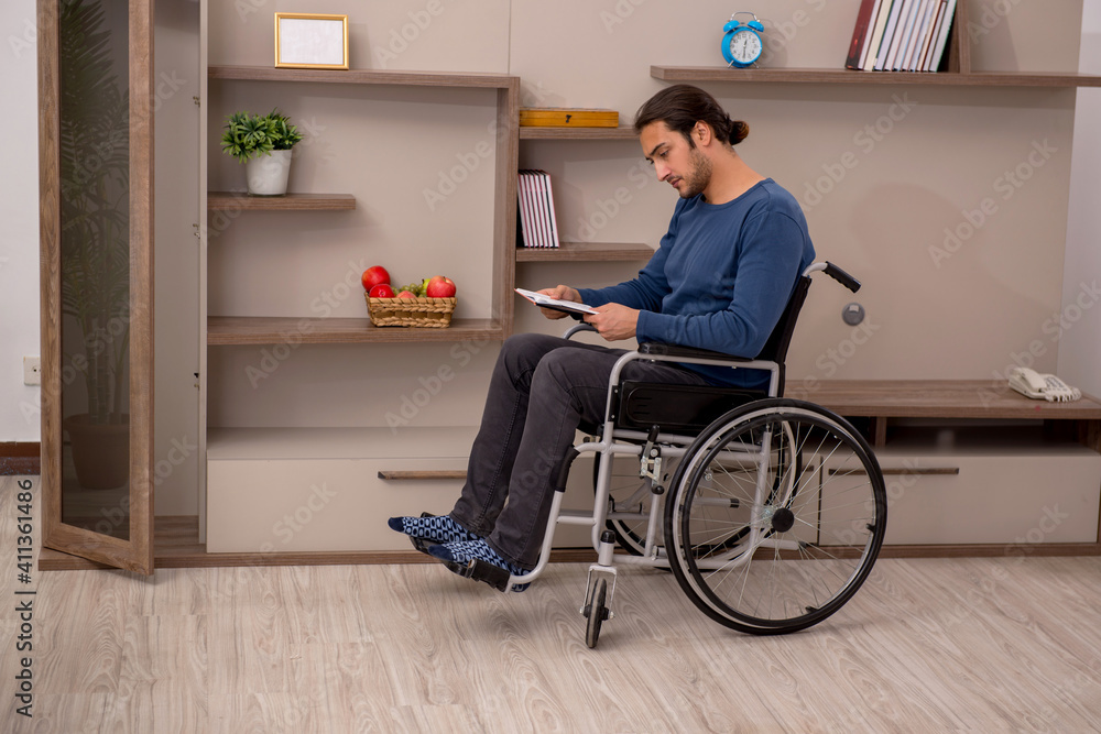 Young man in wheel-chair suffering at home Young man in wheel-chair suffering at home