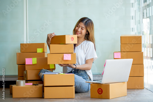 Starting Small business entrepreneur SME freelance,Portrait young woman working at home office, BOX,smartphone,laptop, online, marketing, packaging, delivery, SME, e-commerce concept © David