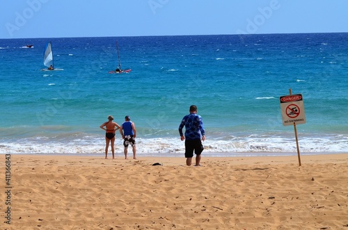 People out enjoying the beach and watching the sail boat in the distance