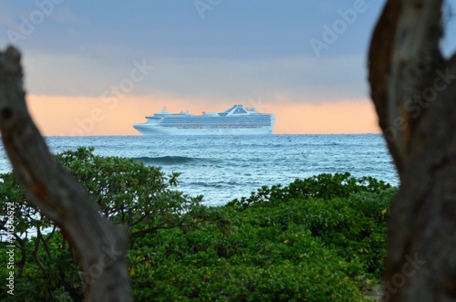 A ship sits anchored just off shore in the early morning, with a stunning sunrise on the horizon
