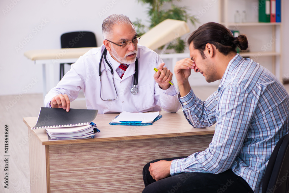 Young male patient visiting aged male doctor Young male patient visiting aged male doctor
