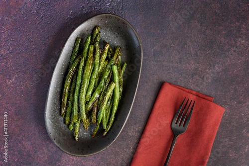 Freshly roasted whole green beans on a serving platter, with a rustic background
 photo