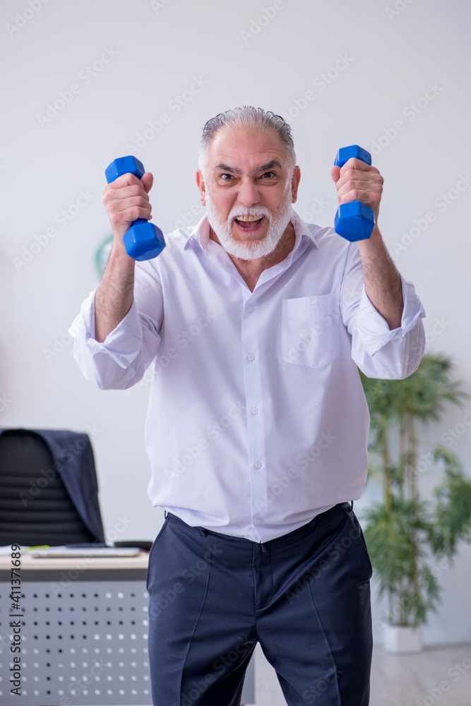 Aged male employee doing physical exercises during break Aged male employee doing physical exercises during break