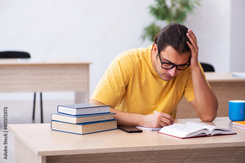 Young male student taking notes during exam preparation Young male student taking notes during exam preparation