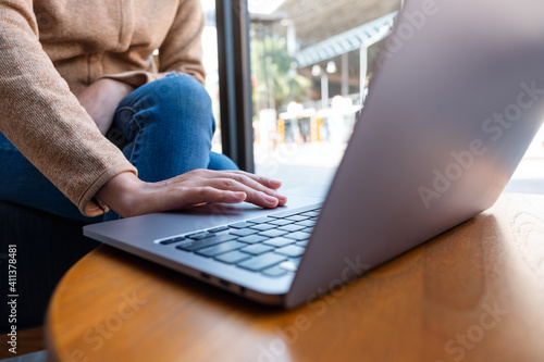 Closeup image of a woman working and touching on laptop touchpad on wooden table