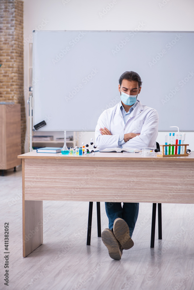Young male chemist teacher sitting in the classroom Young male chemist teacher sitting in the classroom