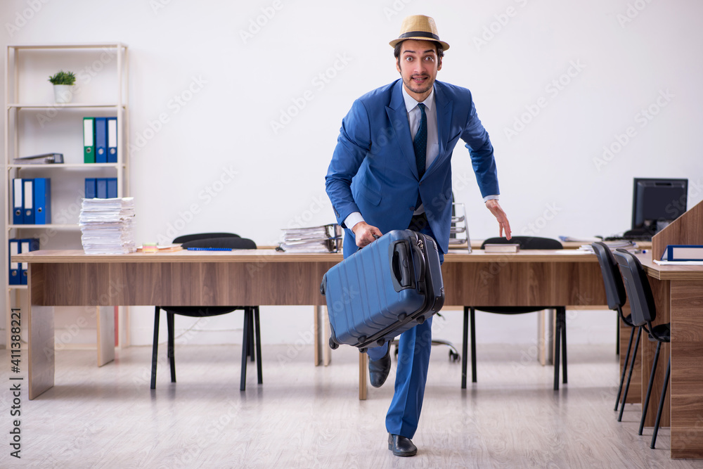 Young male employee preparing for trip in the office Young male employee preparing for trip in the office