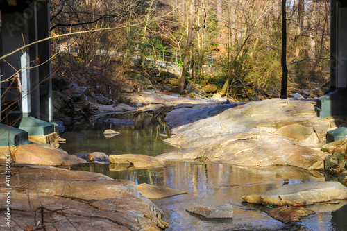 A shot of the still green creek waters with lush green trees and bare tree branches along the banks of the creek with lush green grass at Tanyard Creek Park in the Buckhead area of Atlanta Georgia photo