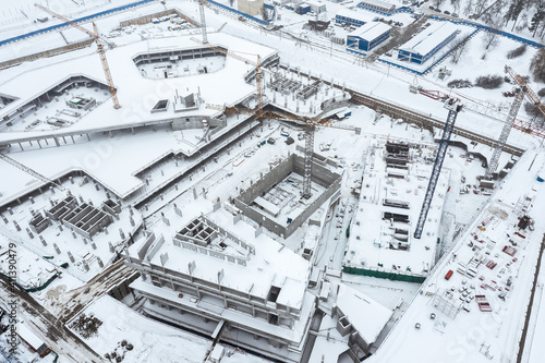 aerial view of city construction site with working cranes in winter time