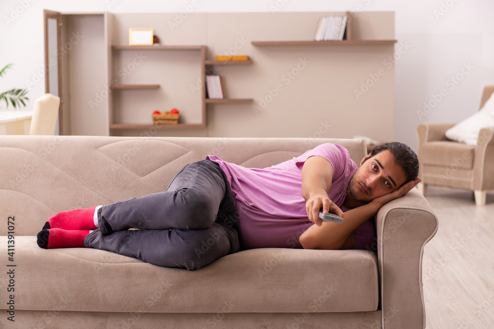 Young man watching tv at home during pandemic