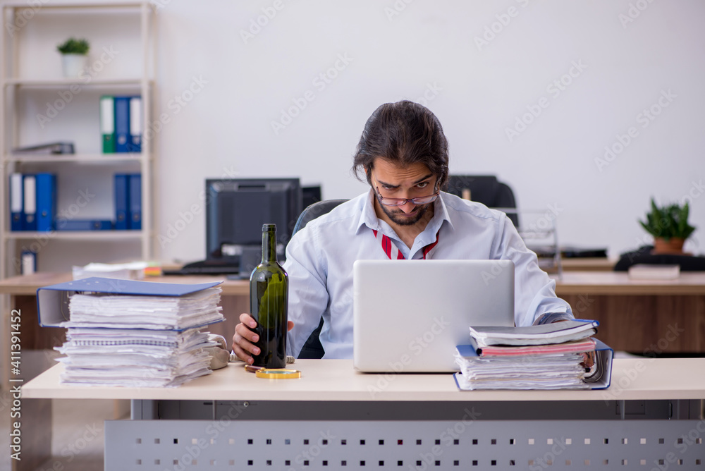 Young male employee drinking alcohol in the office Young male employee drinking alcohol in the office