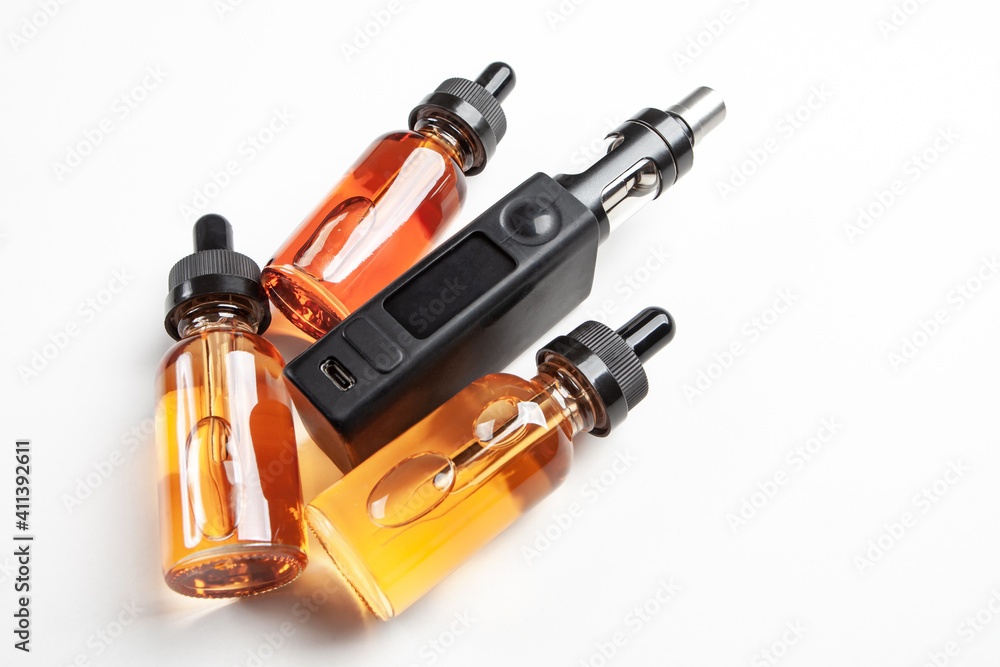Electronic cigarette with a small display. Several bottles of vape juice next to e-cig. Concept of selling electronic devices for smoking. vape juice for refueling e-cigarettes. Vape juice for vaper Electronic cigarette with a small display. Several bottles of vape juice next to e-cig. Concept of selling electronic devices for smoking. vape juice for refueling e-cigarettes. Vape juice for vaper