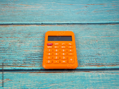 The orange calculator on the wooden background. Business concept.