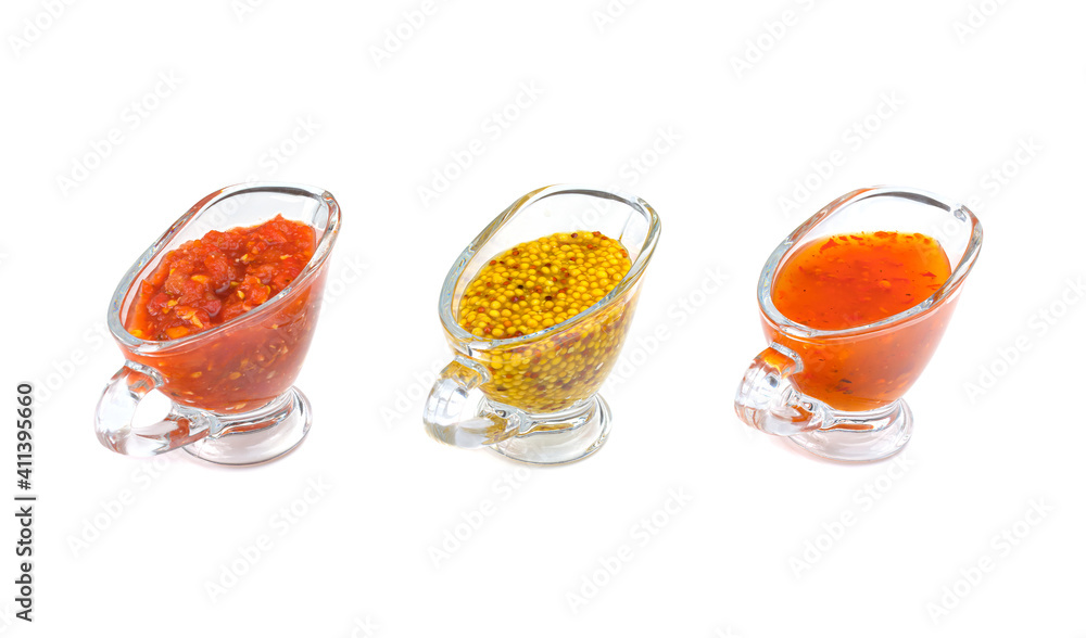 Red delicious ketchup or tomato sauce, adjika and mustard with grains in three clear glass saucepan cups, isolated on a white background. selective focus. Red delicious ketchup or tomato sauce, adjika and mustard with grains in three clear glass saucepan cups, isolated on a white background. selective focus.