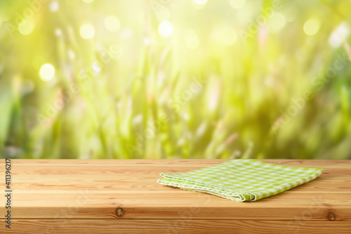 Wall Mural Empty wooden table with tablecloth over green grass blurred background