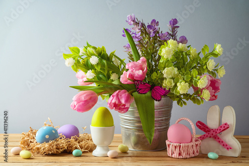 Photography Easter holiday concept with Easter eggs and beautiful tulip flowers bouquet on w