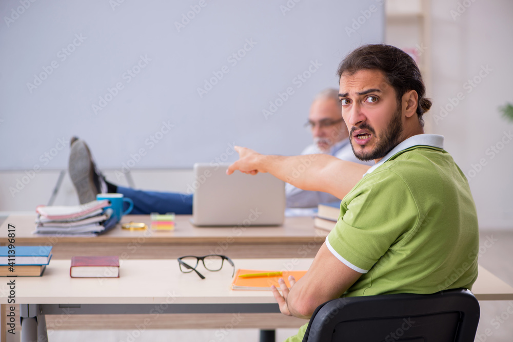 Old male teacher and young male student in the classroom Old male teacher and young male student in the classroom