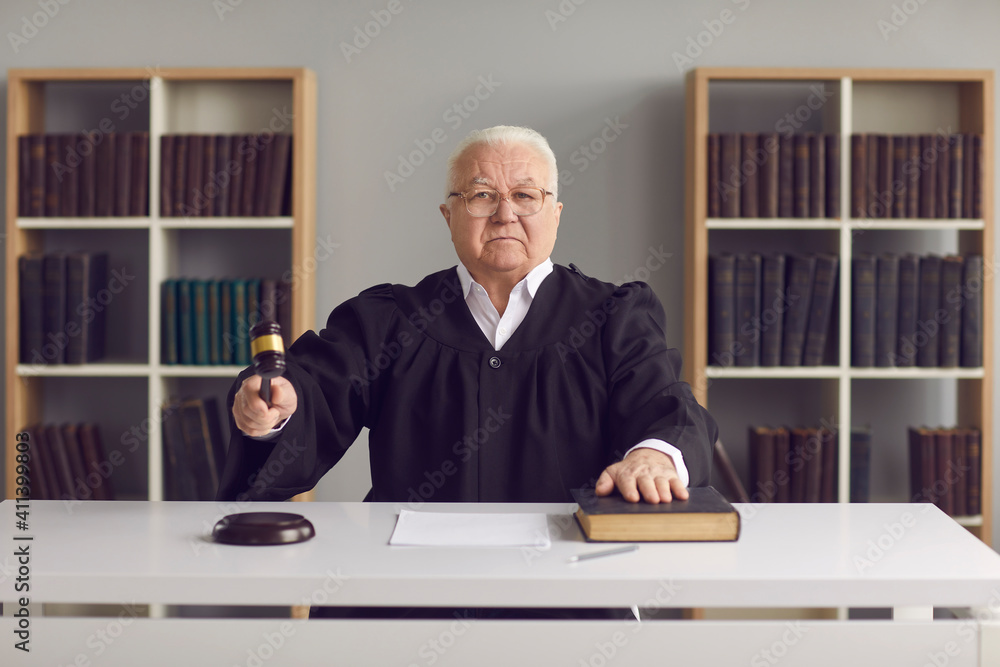 Stern judge in court of law finds the accused guilty, passes judgement and rules case closed. Strict male judge sitting at table in courtroom, hitting sound block with gavel and pronouncing sentence Stern judge in court of law finds the accused guilty, passes judgement and rules case closed. Strict male judge sitting at table in courtroom, hitting sound block with gavel and pronouncing sentence