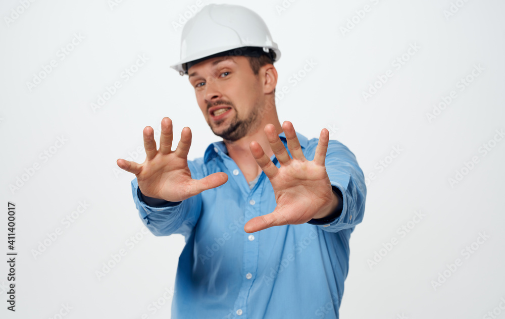 Emotional architect builder in a white helmet and in a blue shirt on an isolated background