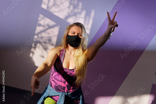 young blonde girl zumba trainer wears black mask during pandemic photo