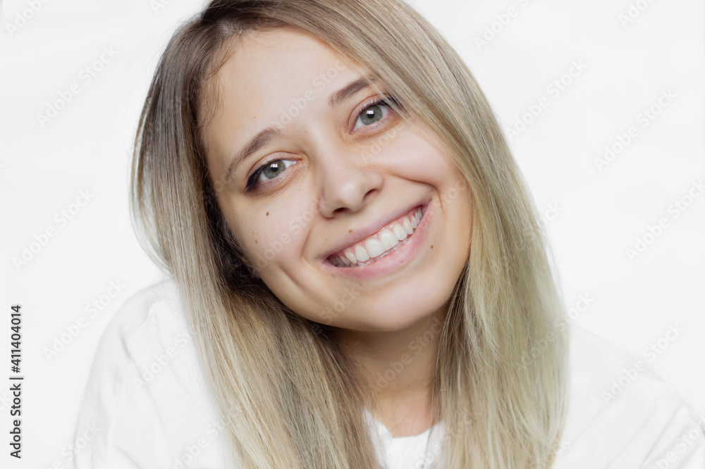 Close up of a caucasian happy blonde smiling girl in a white t-shirt on an isolated white background. Real sincere emotions. Young woman with a beautiful smile and dimples. Natural beauty Close up of a caucasian happy blonde smiling girl in a white t-shirt on an isolated white background. Real sincere emotions. Young woman with a beautiful smile and dimples. Natural beauty