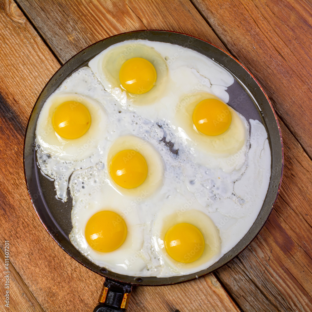 Fried eggs in a frying pan on an old rustic wooden table, top view. Fried eggs in a frying pan on an old rustic wooden table, top view.