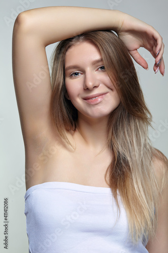 Portrait of young blonde woman with hand up.