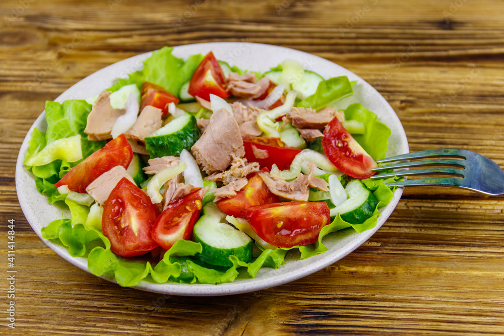 Tasty tuna salad with lettuce and fresh vegetables on wooden table Tasty tuna salad with lettuce and fresh vegetables on wooden table