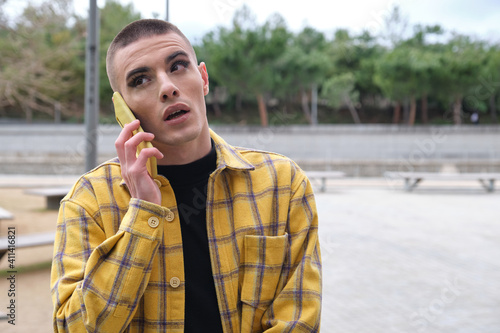 Handsome young man wearing make up, talking on his smartphone. Non binary androgynous guy.
