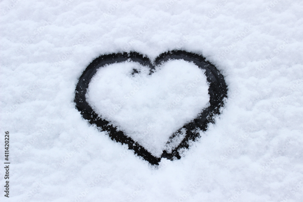Heart shape love sign, drawn on a snow-covered ice on a winter lake with copy space. Romantic backdrop.
