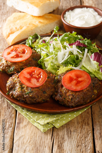 Chapli Kebab or Kabab minced kebab made from ground mutton with various spices in the shape of a patty closeup in the plate on the table. Vertical
