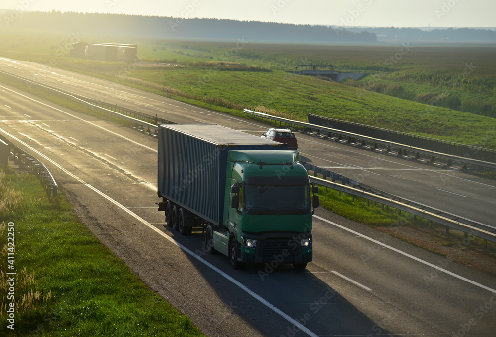 Semi truck transporting sea container on highway on sunset background. Shipping Containers Delivery, Maritime Services and Transport logistics Semi truck transporting sea container on highway on sunset background. Shipping Containers Delivery, Maritime Services and Transport logistics
