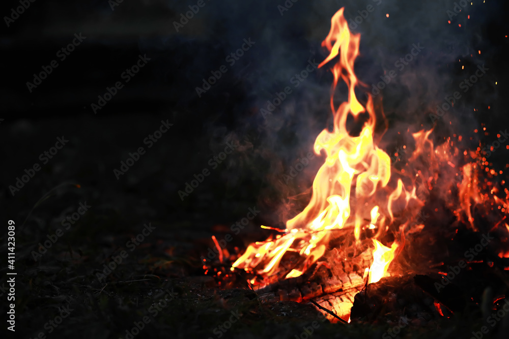 Burning red hot sparks fly from big fire. Burning coals, flaming particles flying off against black background. Burning red hot sparks fly from big fire. Burning coals, flaming particles flying off against black background.
