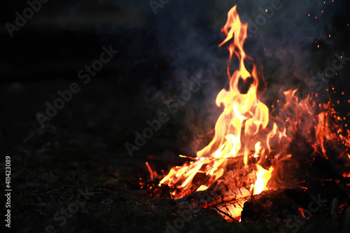 Burning red hot sparks fly from big fire. Burning coals, flaming particles flying off against black background.