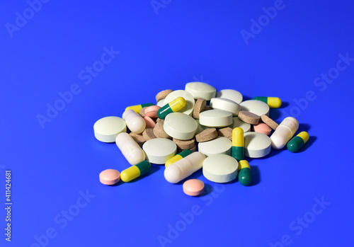 Pills and capsules on blue background. Medicine grade pharmaceutical tablets. Medical pill for maintaining and improving health. Antidepressant addiction and depression concept.