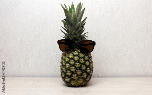 Pineapple in sunglasses. Sunglasses on pineapple on wooden table