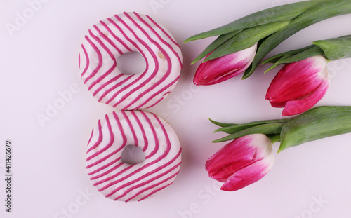 Number eight from donuts on a white background with pink tulips. March 8, International Women's Day