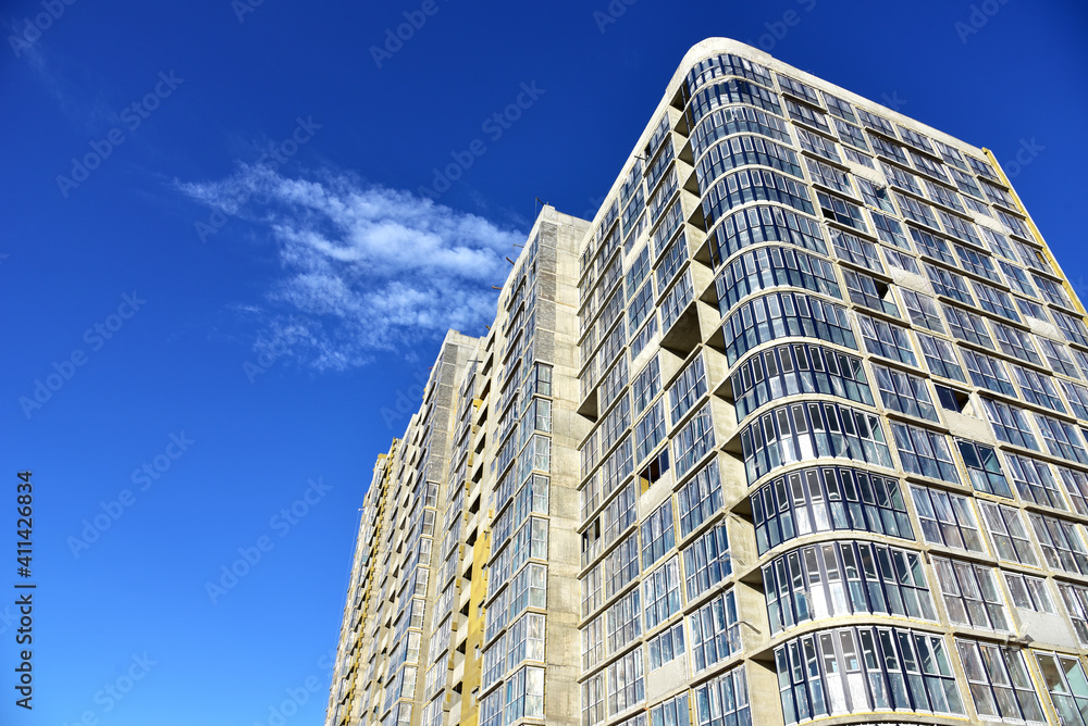 Facade of a new modern high-rise residential building. Skyscraper on blue sky background. Tall house renovation project, government programs. Minimalistic multi storied home. Facade of a new modern high-rise residential building. Skyscraper on blue sky background. Tall house renovation project, government programs. Minimalistic multi storied home.