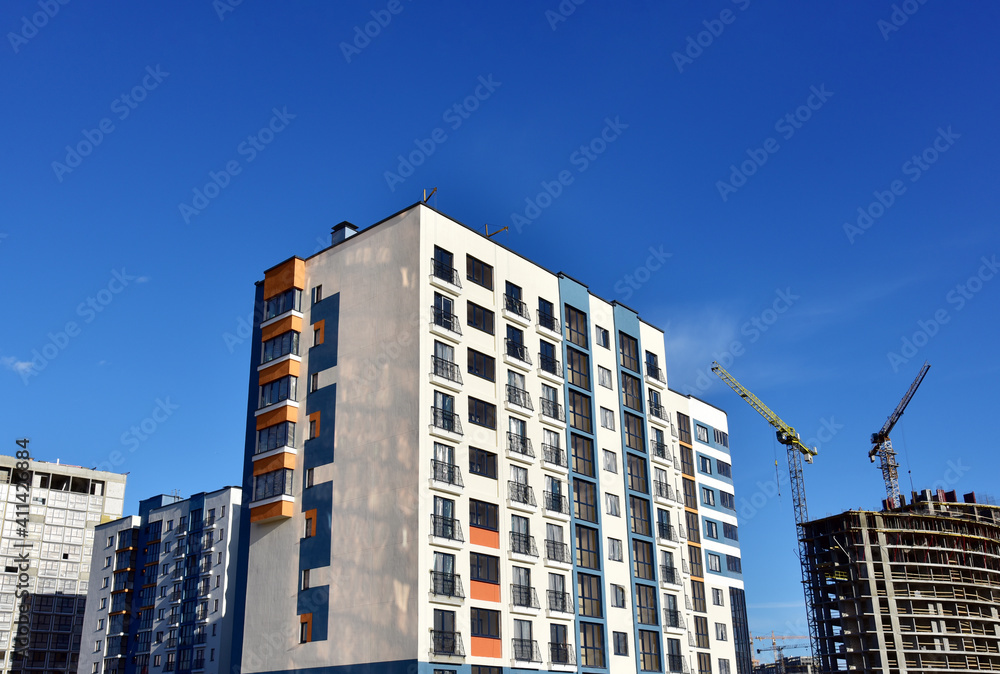 Tower cranes in action on blue sky background. Construction of new multi-storey buildings. Residential building is being constructed use of crane. Pouring of concrete in formwork