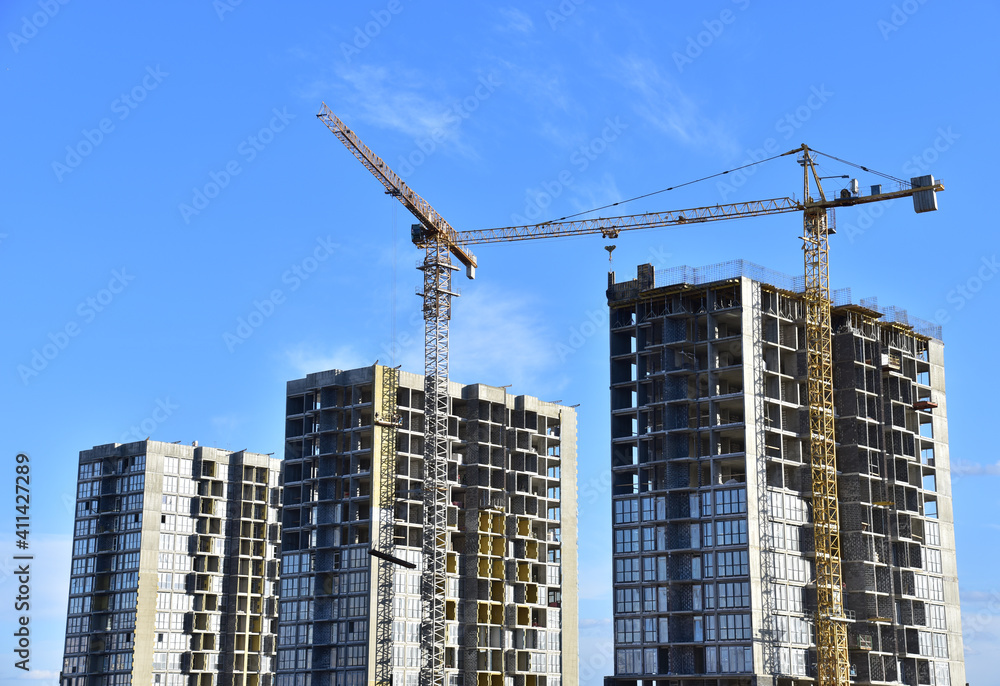 Tower cranes in action on blue sky background. Construction of new multi-storey buildings. Residential building is being constructed use of crane. Pouring of concrete in formwork