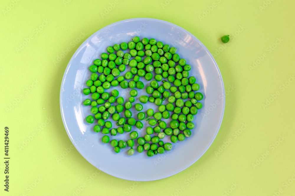 Green peas in a blue plate on a yellow background,top view Green peas in a blue plate on a yellow background,top view